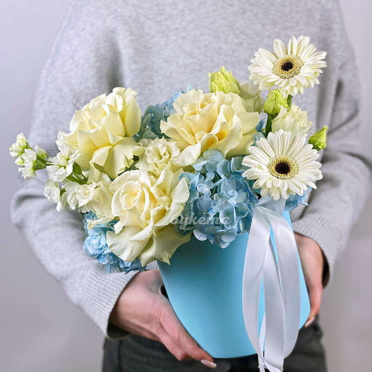 Голубые гортензии с белыми розами в коробке (в руках флориста)